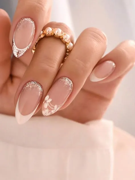 For a perfect look, this wedding nail design combines a classic French manicure with sparkling glitter and delicate floral art.